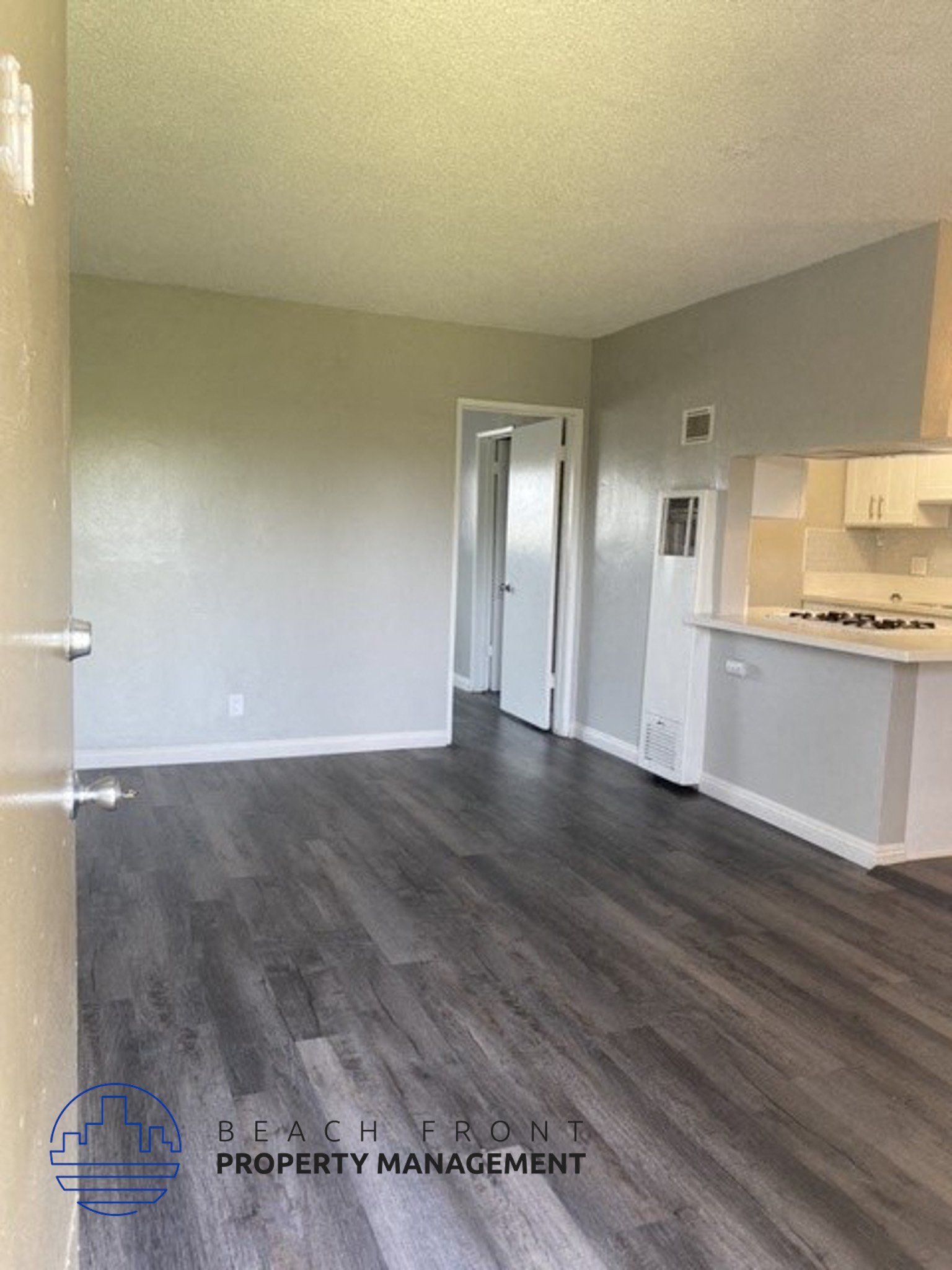 an empty living room and kitchen with wood floors